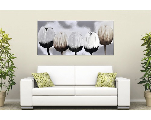 Dekorativní obraz tulipánů nad bílou pohovkou s polštáři a hrnkovými rostlinami