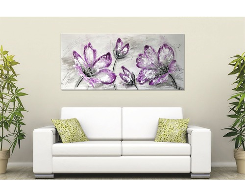 Dekorativní nástěnný obraz s květinovým motivem nad pohovkou v obývacím pokoji.