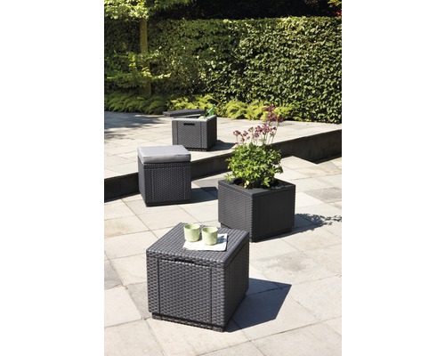 Zahradní scéna s úložnými boxy, sedací stoličkou s polštářem a květináčem s ratanovým vzhledem na terase.