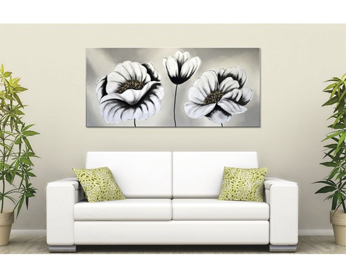 Obývací pokoj s bílou pohovkou, zelenými polštáři a obrazem s květinovými motivy.