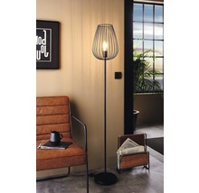 Kovová stojací lampa s drátěným stínidlem v obývacím pokoji.