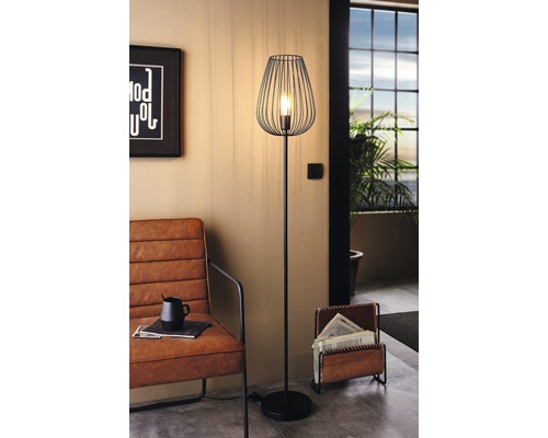 Kovová stojací lampa s drátěným stínidlem v obývacím pokoji.