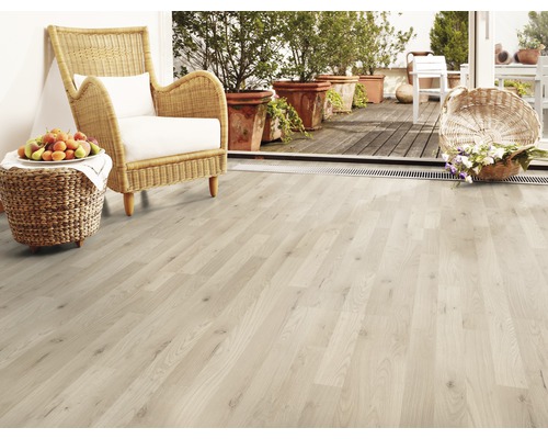 Světlá dřevěná podlaha s proutěným křeslem, ovocem a květinami na terase