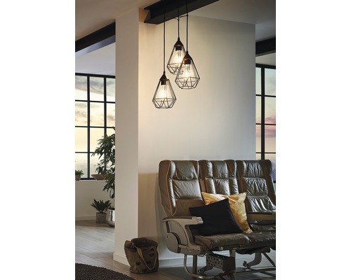 Závěsná lampa se třemi svítidly nad pohovkou v obývacím pokoji.