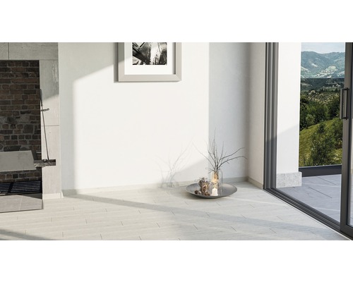 Světlá místnost s kamennou podlahou, krbem, dekorací a výhledem ven