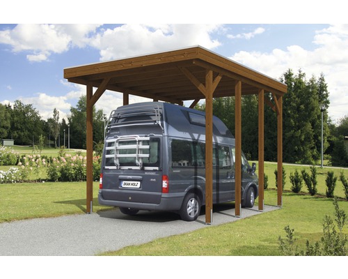 Dřevěný přístřešek pro auto s šedou dodávkou na štěrkové cestě