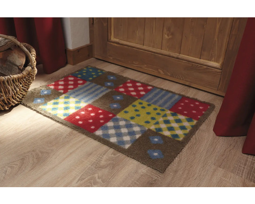 Barevná rohožka s různými vzory před dveřmi.