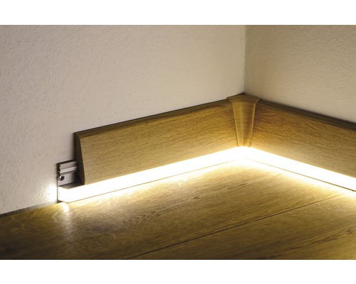 Roh s dřevěnou podlahovou lištou a nepřímým osvětlením