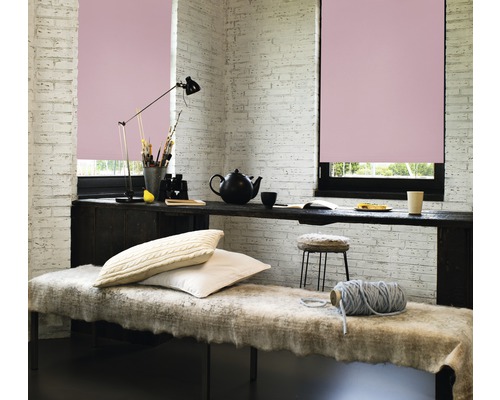 Světlá místnost se dvěma okny a růžovými roletami, zdobená lavicí, stolem a doplňky