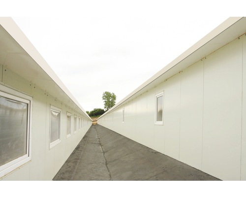 Dlouhá chodba mezi dvěma řadami kancelářských kontejnerů s okny