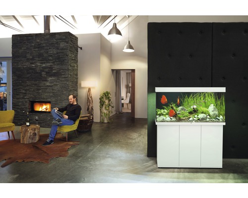 Obývací pokoj s akváriem a mužem sedícím u krbu.