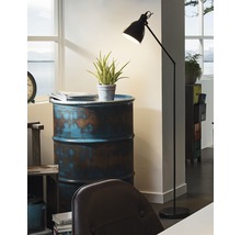 Stojací lampa vedle odkládacího stolku vyrobeného z lakovaného sudu v místnosti