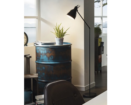 Stojací lampa vedle odkládacího stolku vyrobeného z lakovaného sudu v místnosti