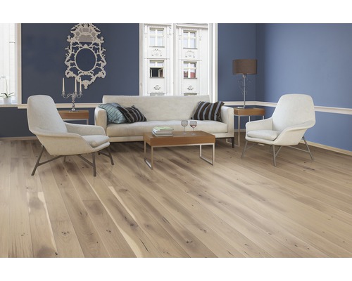 Světlý obývací pokoj s dřevěnou podlahou, pohovkou a křesly pro útulnou atmosféru.