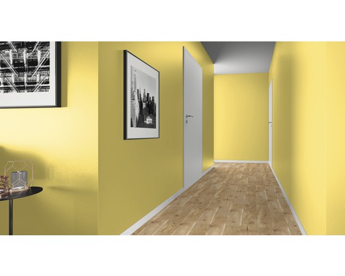 Chodba se žlutými stěnami, dřevěnou podlahou a bílými dveřmi.