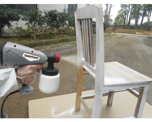 Stříkací pistole na barvu stříkající dřevěnou židli