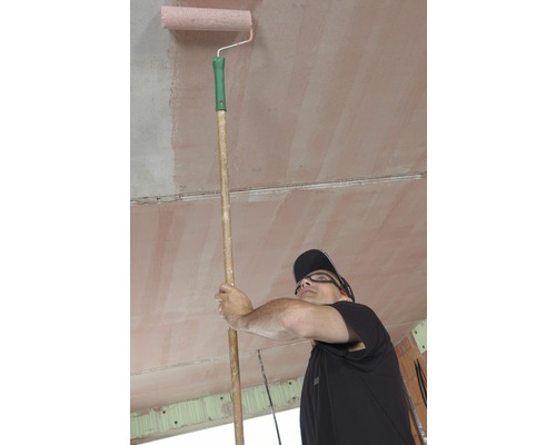 Muž natírá strop válečkem na malování na tyči