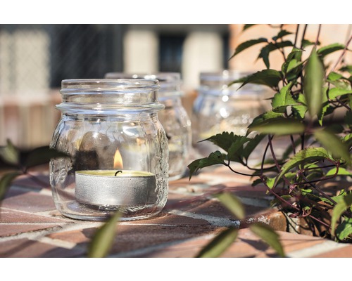 Skleněná lucerna s čajovou svíčkou na cihlovém povrchu