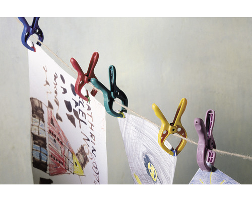 Barevné kolíčky drží dětské kresby na šňůře na prádlo