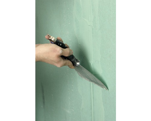 Ruka s špachtlí při tmelení sádrokartonové stěny