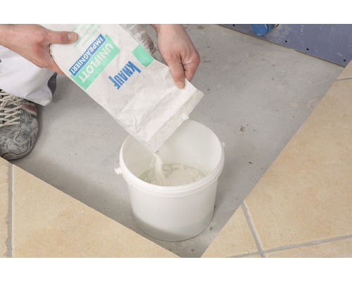 Osoba sype spárovací hmotu Knauf Uniflott impregnovaná do kbelíku