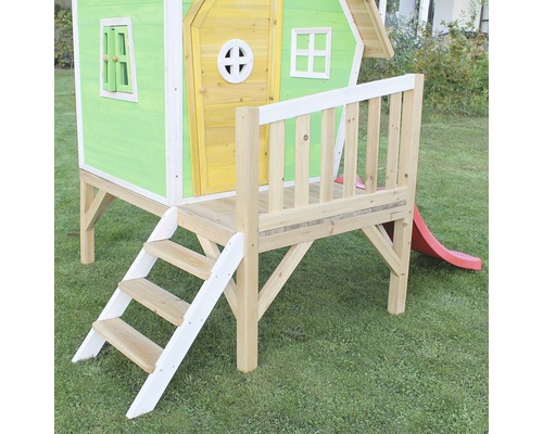 Hrací domek se schody a skluzavkou na zahradě.