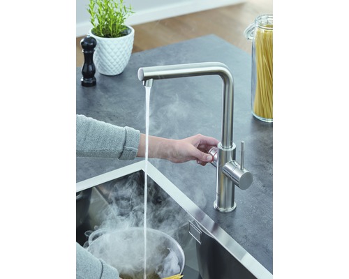 Kuchyňská scéna s vodovodní baterií, kohoutkem a vroucí vodou v umyvadle.