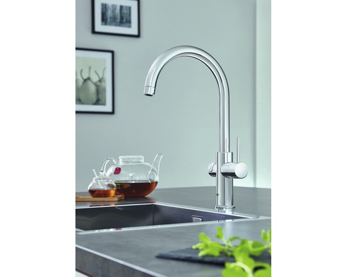 Chromová kuchyňská baterie s vysokým výtokem a pákovou směšovací baterií vedle umyvadla.