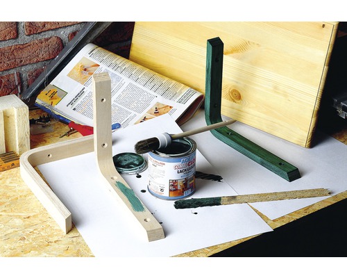 Dílenská scéna s dřevěnými kusy, plechovkou barvy, štětcem a barvou