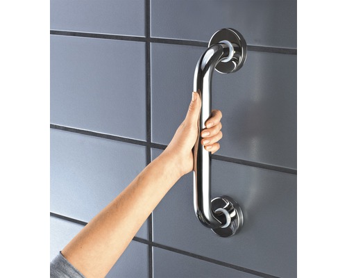 Ruka drží madlo z nerezové oceli na zdi