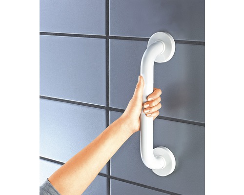 Ruka drží bílé madlo v koupelně na zdi