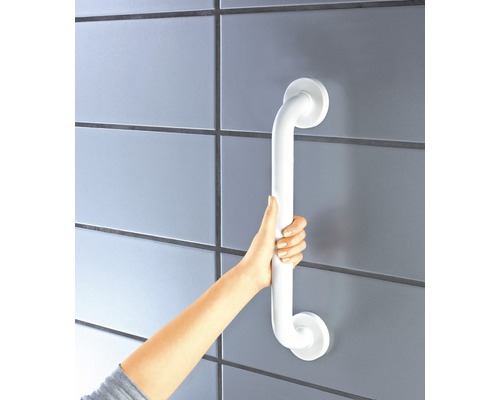 Osoba drží bílé madlo na zdi.