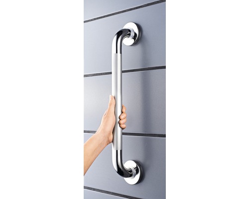 Osoba drží stříbrné madlo na zdi