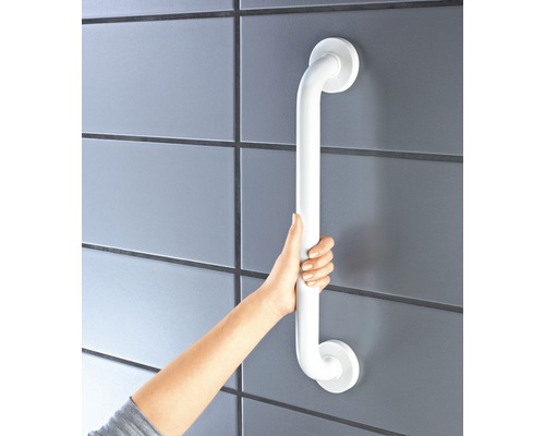 Osoba drží bílé madlo připevněné k obložené zdi.