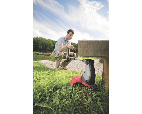 Muž používá vyžínač na trávu na zahradě.