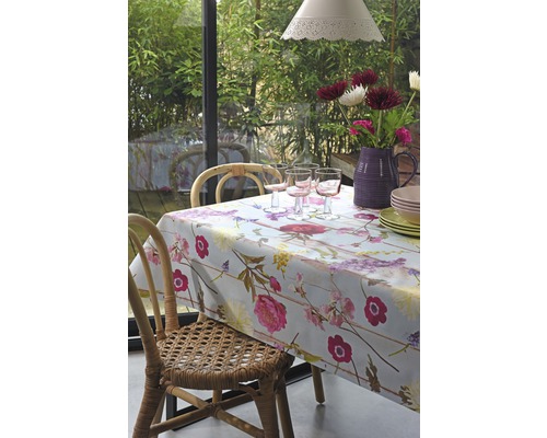 Jídelní stůl s květinovým ubrusem, sklenicemi, nádobím a květinami ve váze