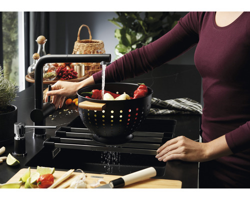 Dřez s odkapávačem, baterií a ženou myjící zeleninu