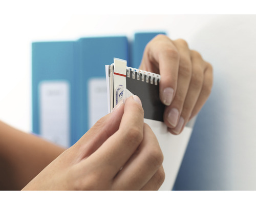 Ruce odstraňují nálepku z poznámkového bloku.