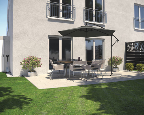 Terasa se zahradním stolem, židlemi a slunečníkem vedle obytného domu.