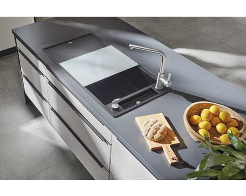 Dřez s prkénkem na krájení, armaturou, chlebem na prkénku a miskou s citrony na pracovní desce