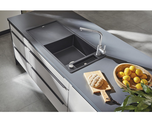 Dřez s baterií, prkénko, chléb a citrony na kuchyňské lince