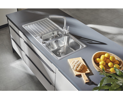 Nerezový kuchyňský dřez s odkapávací plochou a baterií na kuchyňské desce