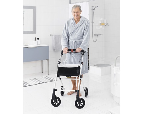 Muž v županu s chodítkem v koupelně.