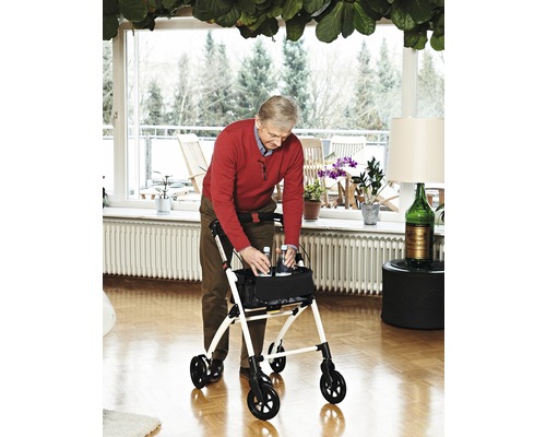 Muž používá chodítko v světlém obývacím pokoji.