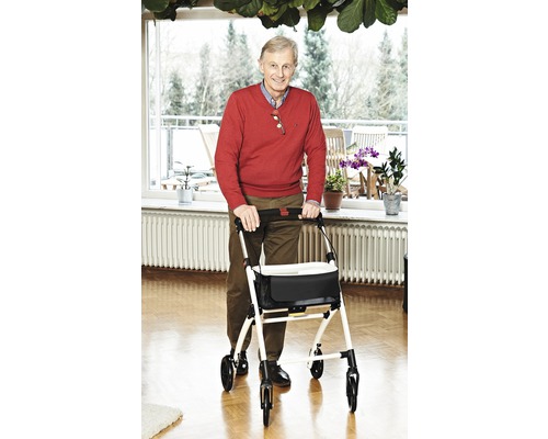 Muž s chodítkem v světlém obývacím pokoji.