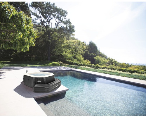 Nafukovací vířivka značky Intex vedle bazénu na zahradě.