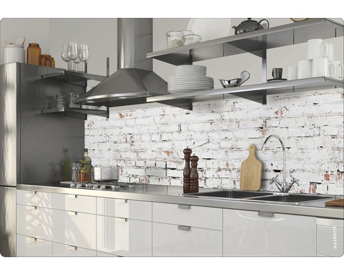 Moderní kuchyně s nerezovými spotřebiči a pracovní deskou před stěnou se vzorem cihel