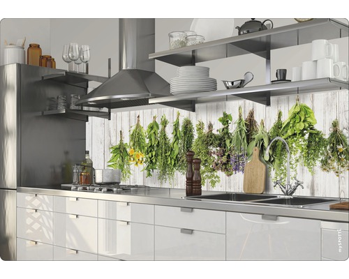 Kuchyňská scéna s bílými skříňkami, nerezovým dřezem a motivem bylin na zadní stěně