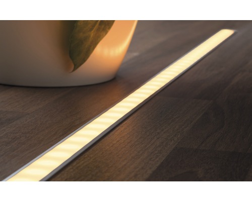 LED pásek na dřevěné podlaze vedle rostliny
