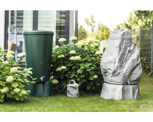 Zahradní scéna se zeleným a šedým zásobníkem na dešťovou vodu ve vzhledu kamene a konví